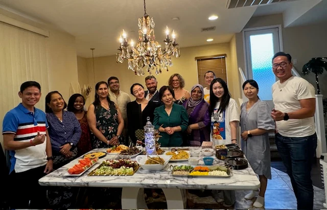 Hosts and international visitors standing around a table of Korean dishes in the photograph published with the WACLV account